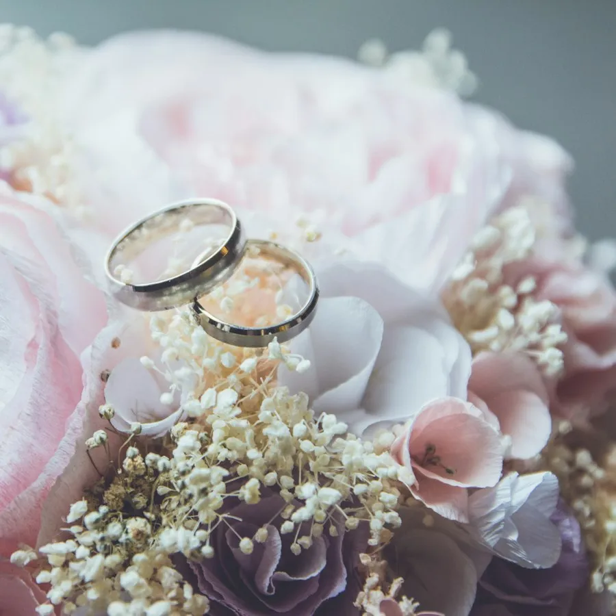 Zwei goldene Eheringe auf rosa Rosen und Schleierkraut